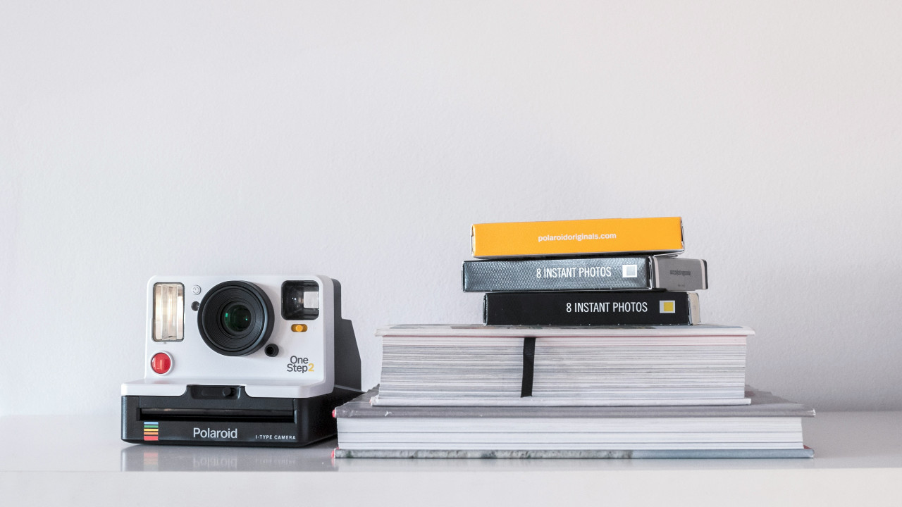 polaroid camera next to photo albums